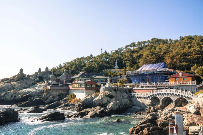 A bridge over a body of water next to a lush green hillside